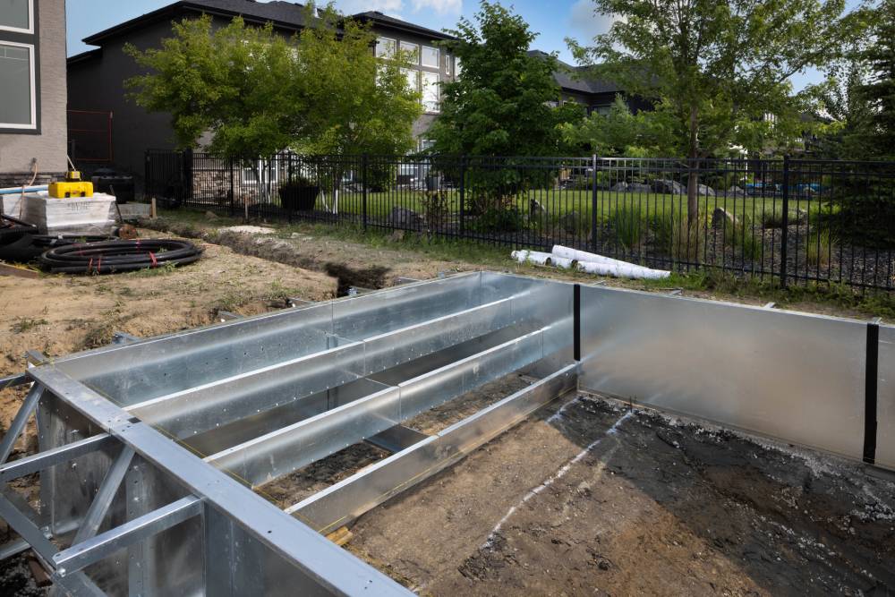 Close up of stairs in 14’ x 28’ steel pool kit during construction A man wearing an apron operates a metal grinder, creating sparks as he works in a workshop environment.