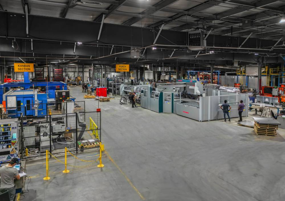 Inside Malach Metal & Machining production facility Two construction workers in hard hats and helmets are positioned at a construction site, engaged in their tasks.